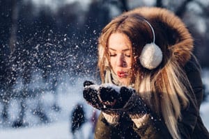 Woman ear muffs mittens blowing snow