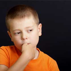 little boy with autism with hand in mouth