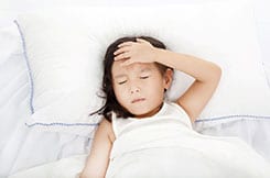 Girl laying on white pillow and sheets not feeling well