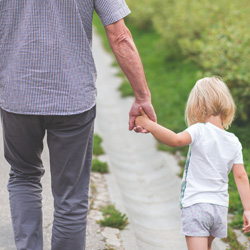 grandparent holding granddaughters hand while walking